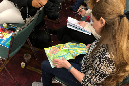 two seated somen looking at apicture book and taking notes